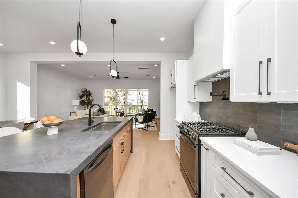 The custom vent hood above the gas range adds a unique touch, while the black pot filler, perfectly positioned above the stove, provides easy access to water, streamlining your cooking experience with maximum efficiency.