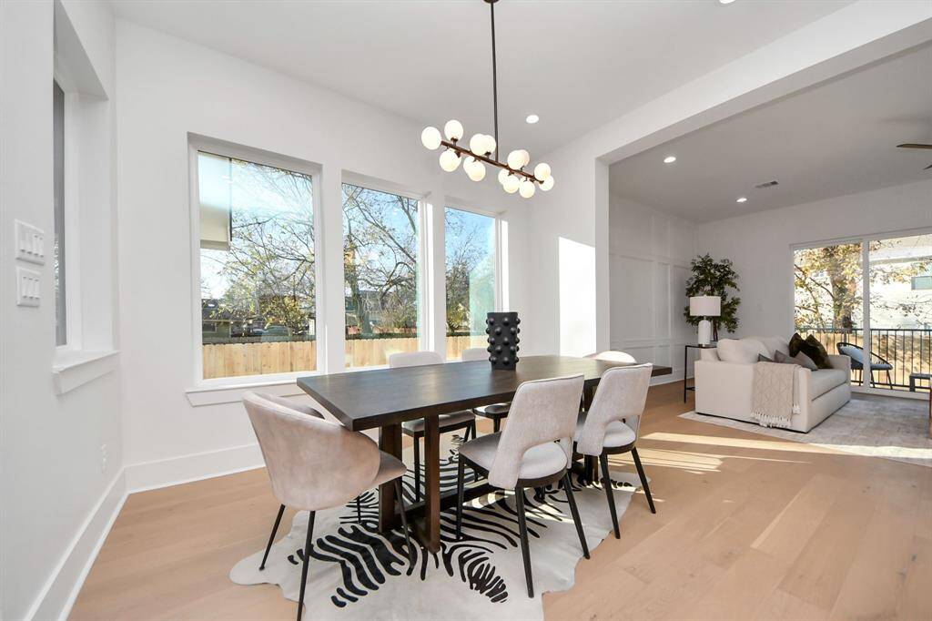 The dining room seamlessly integrates into the open floorplan, bathed in natural light from the large 4-panel windows, creating a bright and inviting space.