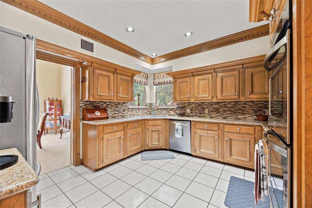 This stunning space features granite countertops complemented by a stylish stone backsplash, creating a harmonious blend of elegance and functionality. Equipped with top-of-the-line stainless steel appliances, it invites culinary creativity at every turn.