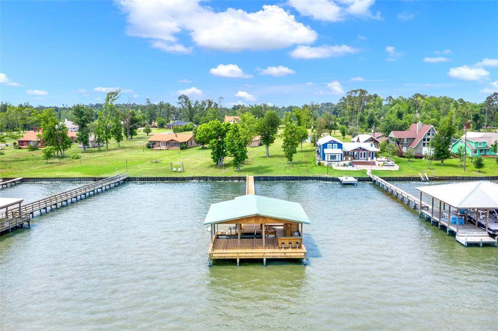 Charming waterfront property with a private dock, boathouse, garage that includes an additional storage area all extending into a serene lake. The property is surrounded by lush greenery and neighboring houses, offering a peaceful, scenic retreat. Ideal for enjoying lakefront living.