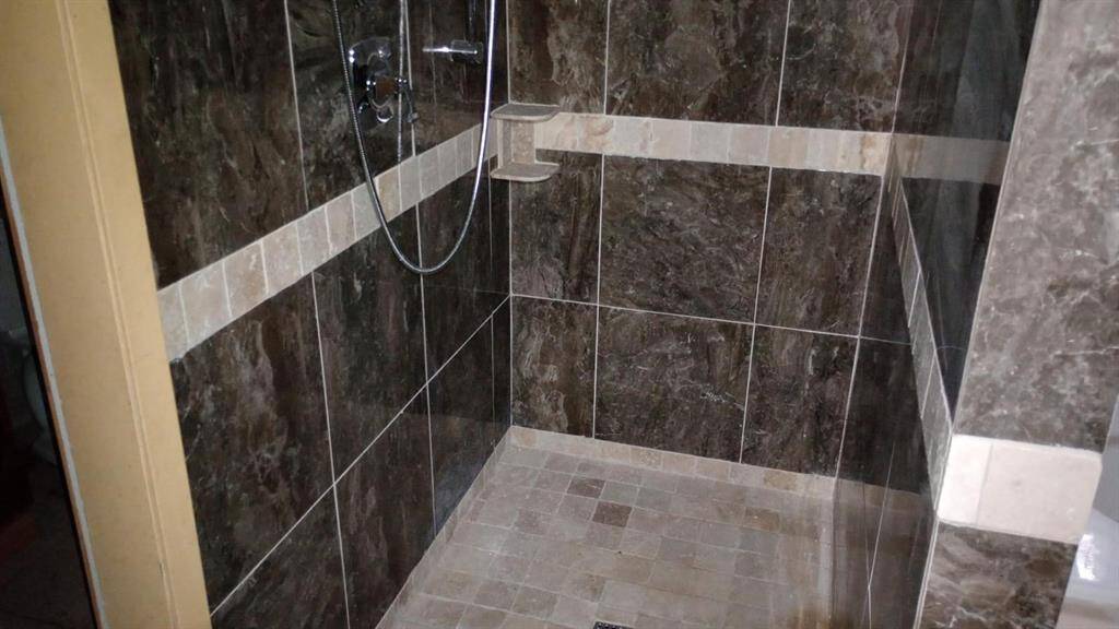 This photo shows a modern shower with elegant dark marble tiles and a built-in shelf. The sleek design creates a luxurious, contemporary feel.
