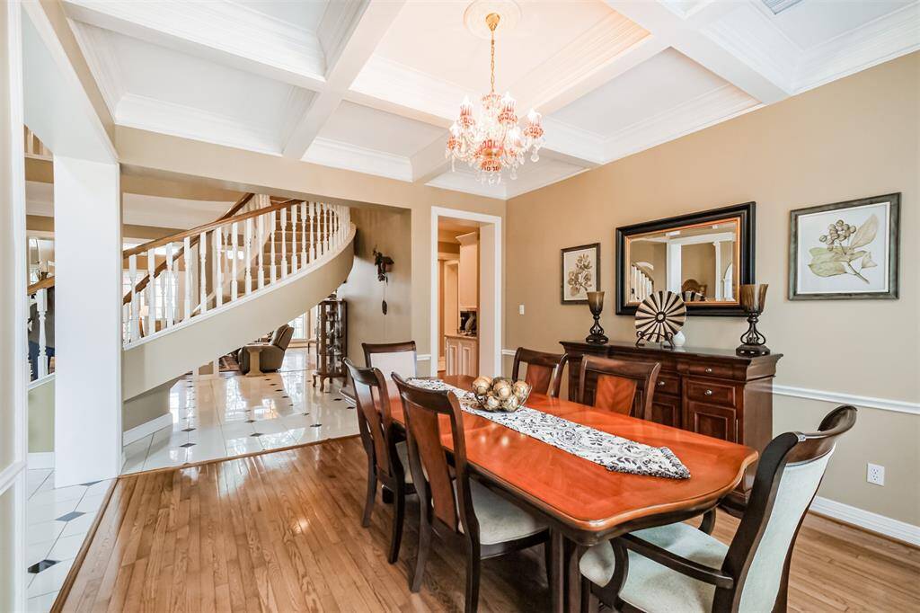 DINING ROOM WITH A WALL OF WINDOWS IS FILLED WITH NATURAL LIGHT, THIS ROOM BOASTS WOOD FLOORING AND A CUSTOM CHANDELIER.
