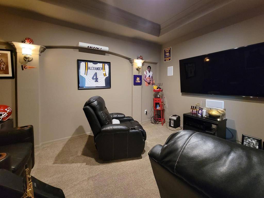 This cozy home theater features plush leather recliners, sports memorabilia, and a large wall-mounted TV, creating an inviting entertainment space.