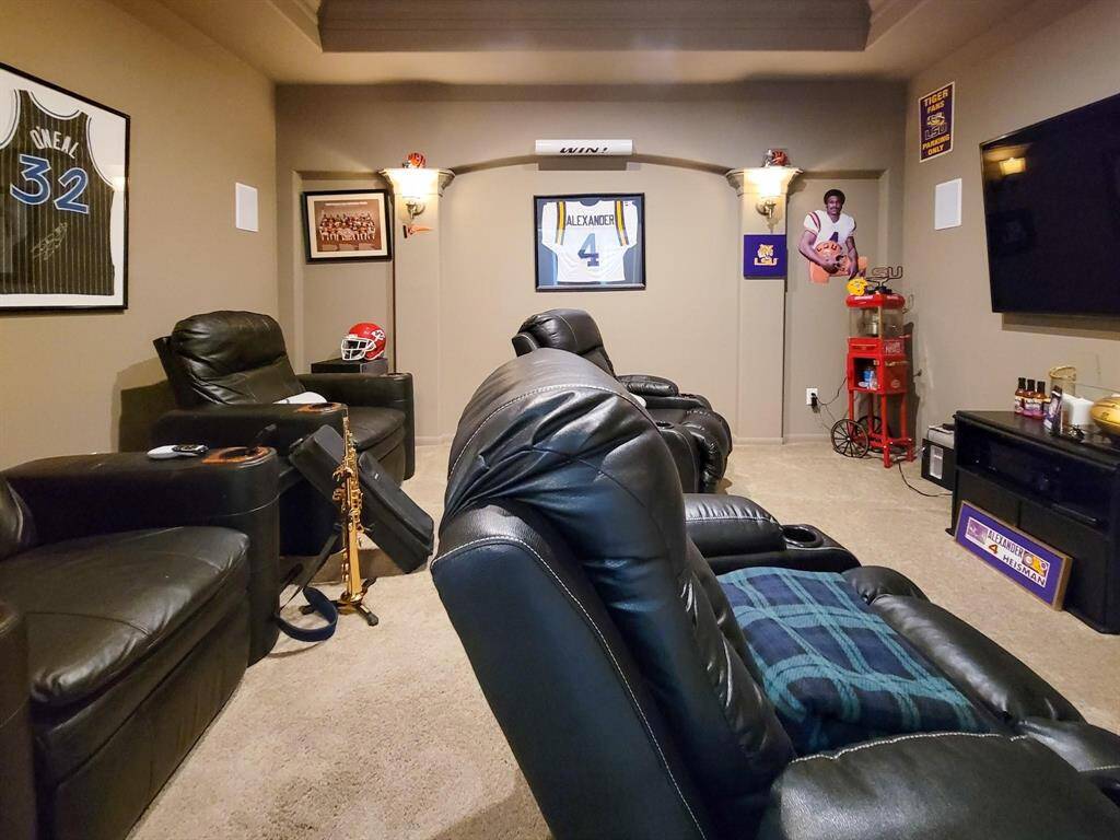 Cozy home theater room with plush leather recliners, sports memorabilia on the walls, and a large TV, perfect for entertainment and relaxation.
