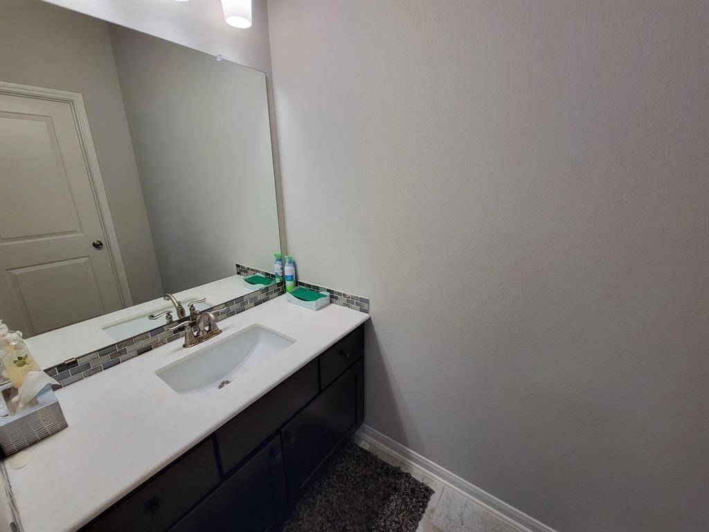 Modern bathroom with a sleek vanity featuring a large mirror and stylish faucet. The space is well-lit with neutral walls and a tile floor, offering a clean and inviting atmosphere.