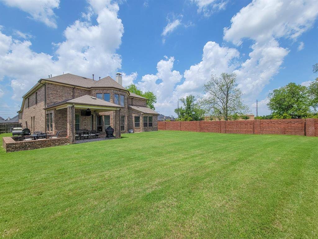 Want to add a pool to this backyard? The yard is enclosed by a red brick wall, offering both privacy and an expansive area for outdoor activities.