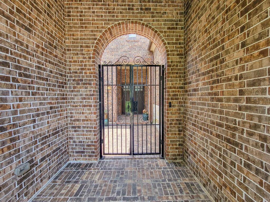 Charming brick entryway with an elegant wrought iron gate, offering a welcoming and secure entrance to the home.