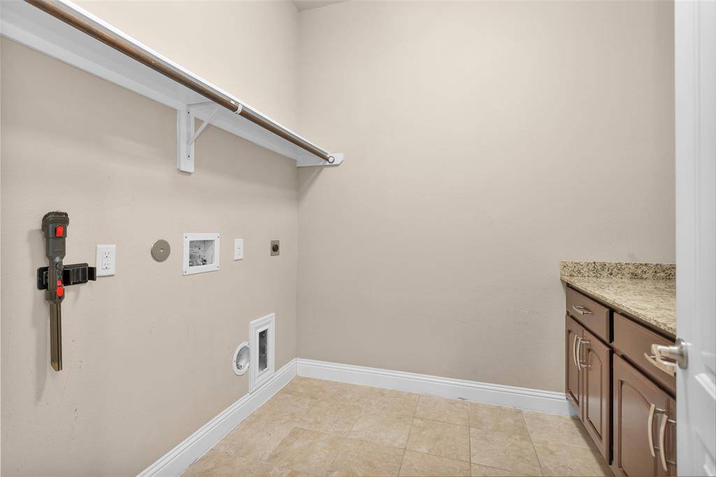 Spacious laundry room with storage space featuring a granite countertop with wooden cabinets below for storage.