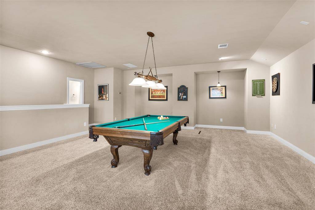 Spacious, upstairs game room features a central pool table (pool table can stay!), soft carpeting, and ample lighting. Ideal for entertaining or family fun!