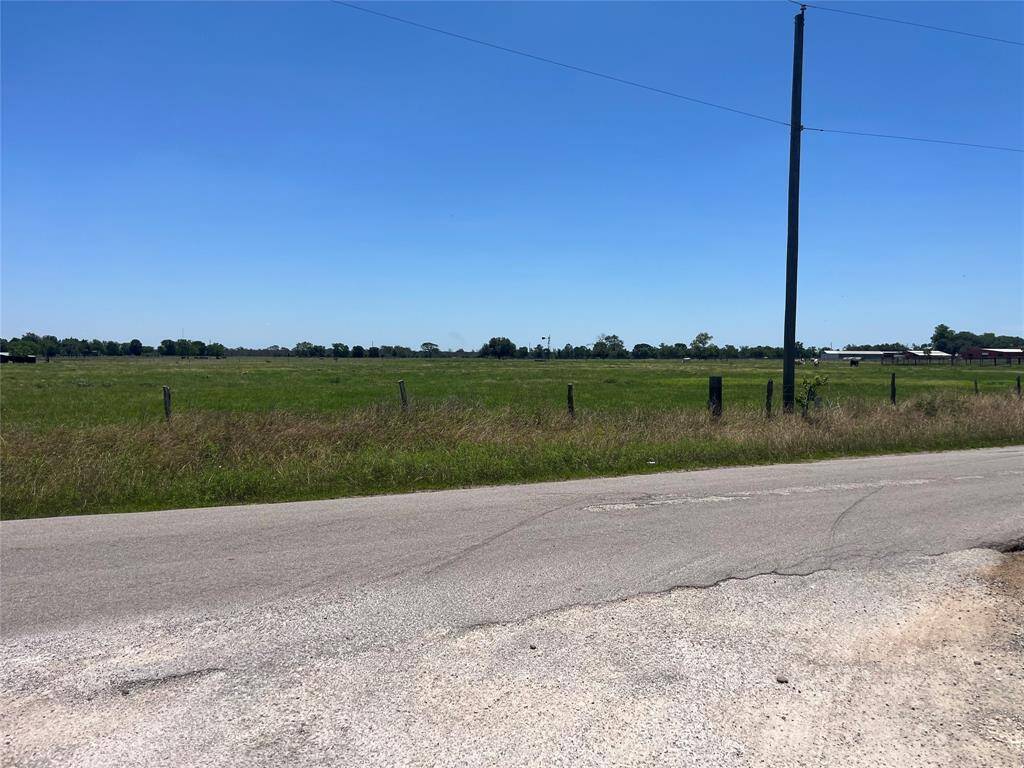 Expansive open field across from 935, bordered by a rural road and fencing.