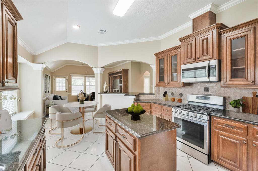 Chef's eat-in island kitchen features 42" solid wood custom cabinets with crown molding, stainless steel appliances, lengthy granite countertops and a breakfast bar