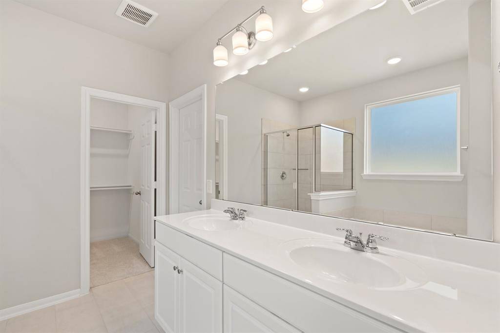 The en-suite bathroom offers a spa-like atmosphere with its elegant design, high end finishes, and tasteful lighting, creating a retreat within your own home.