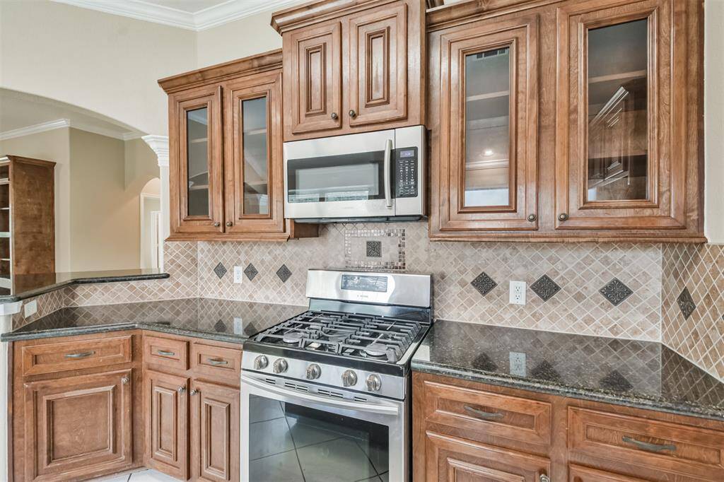 Chef's eat-in island kitchen features 42" solid wood custom cabinets with crown molding, stainless steel appliances, lengthy granite countertops and a breakfast bar