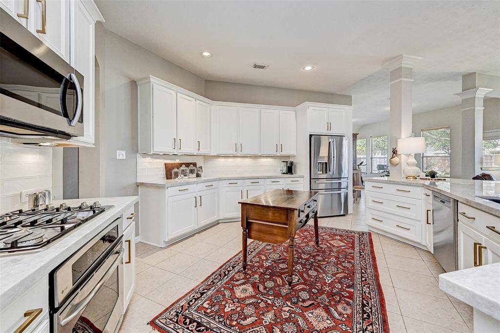 This kitchen features modern stainless steel appliances, white cabinetry with sleek hardware and ample Quartz counter space.