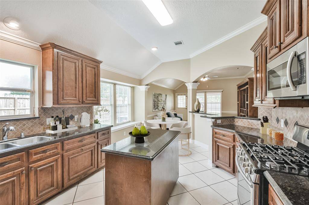Chef's eat-in island kitchen features 42" solid wood custom cabinets with crown molding, stainless steel appliances, lengthy granite countertops and a breakfast bar