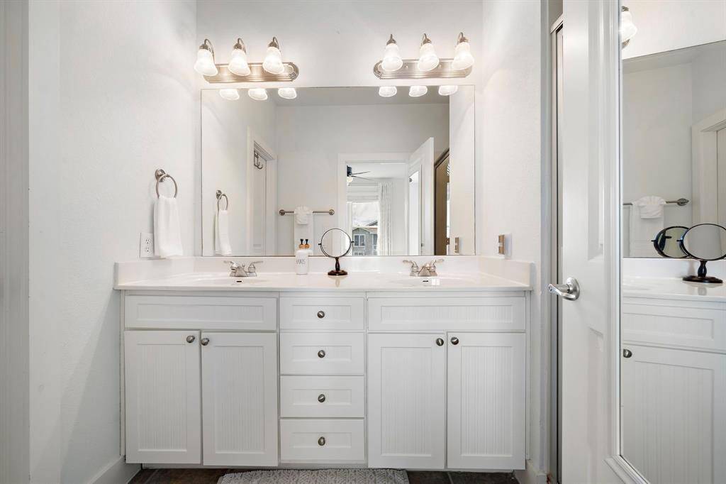 Primary bathroom double vanities with ample lighting and storage.