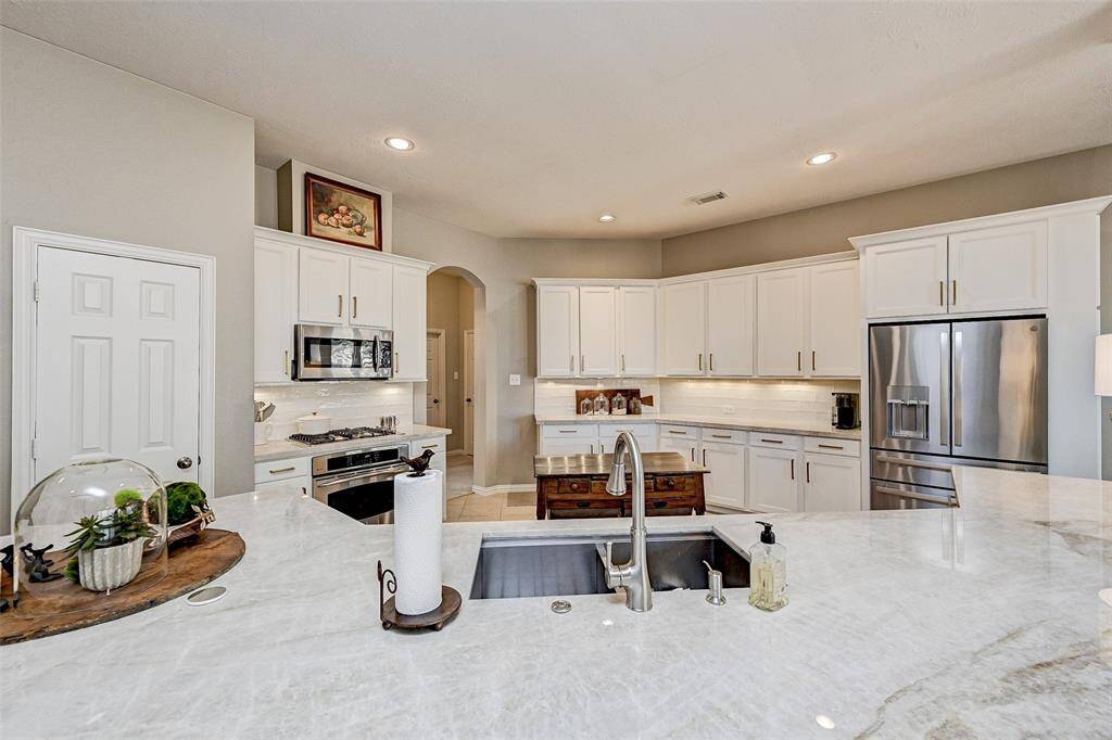 This modern kitchen features an abundance of counter space. The open layout is complemented by recessed lighting and a neutral color palette, offering a bright and inviting space.