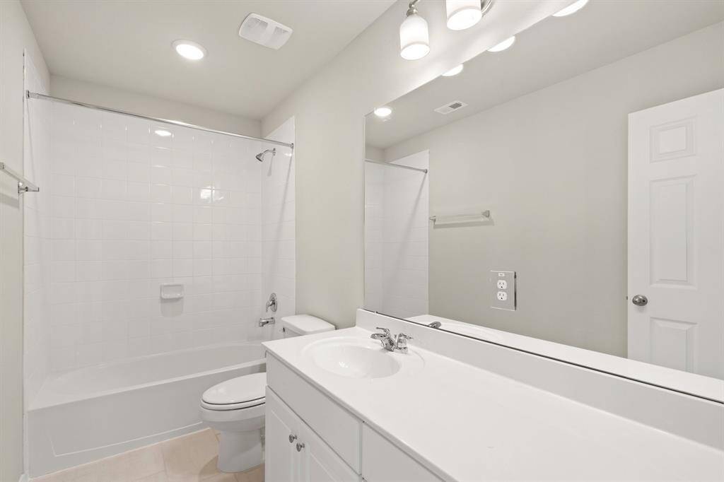 The secondary bath features tile flooring, white cabinetry and light countertops and a shower/tub combo. Perfect for accommodating any visiting family and friends.