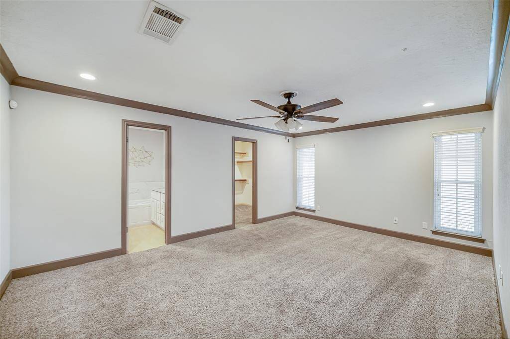 Another view of the primary suite with doors leading to the on-suite bathroom and closet.
