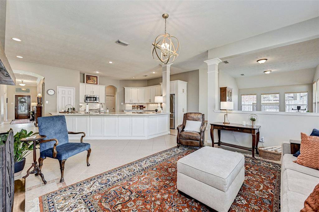 This photo showcases a spacious open-plan living area with a modern kitchen. The living area has comfortable seating and plenty of natural light from multiple windows, creating a warm and inviting atmosphere.