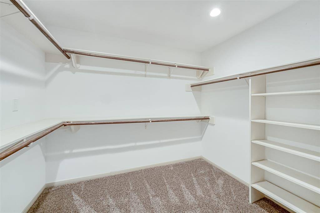 The primary closet a large walk in room with shelving and double clothing rods!