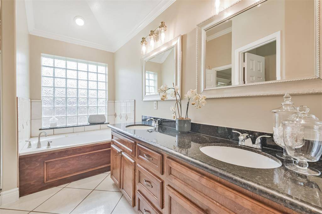 Primary bathroom features granite countertops, double sinks, a walk-in shower, soaking tub, framed mirrors and a walk-in closet