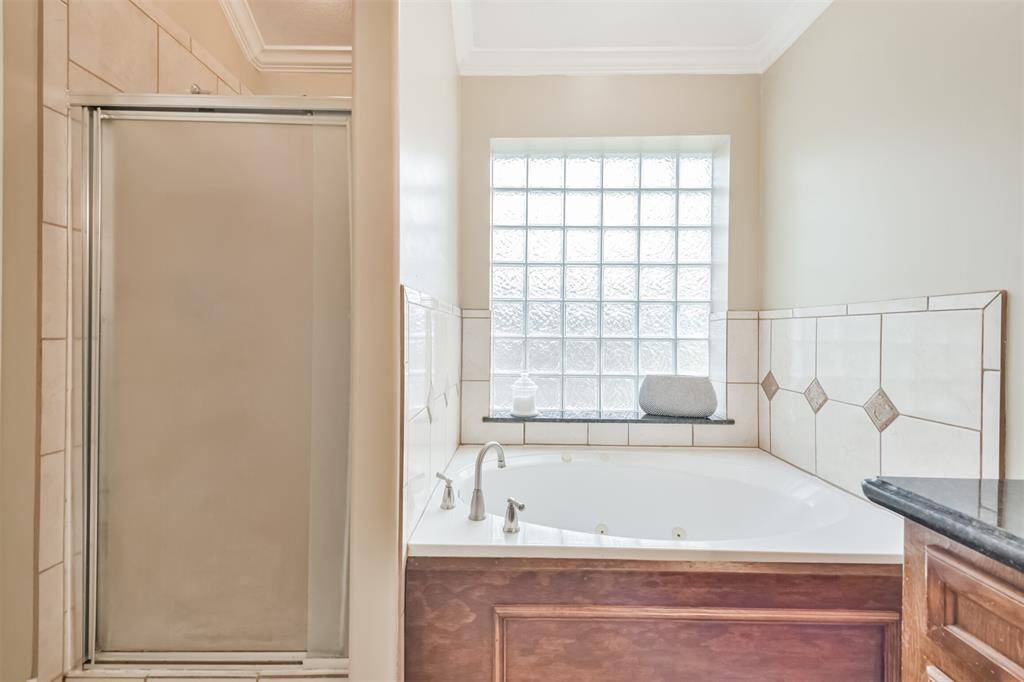 Primary bathroom features granite countertops, double sinks, a walk-in shower, soaking tub, framed mirrors and a walk-in closet