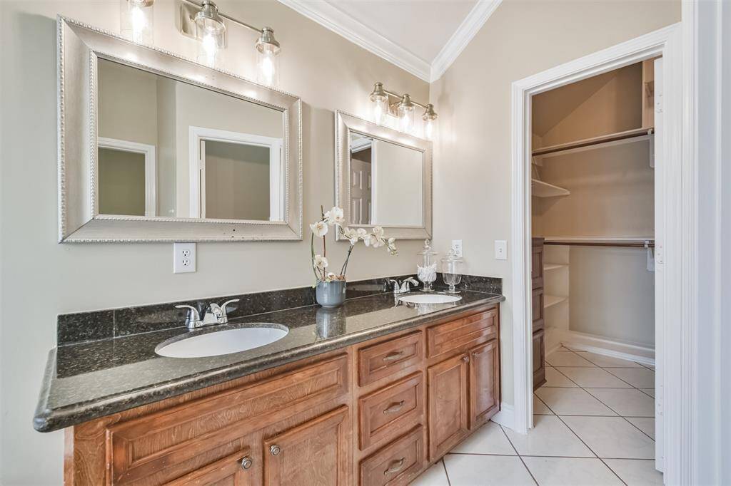 Primary bathroom features granite countertops, double sinks, a walk-in shower, soaking tub, framed mirrors and a walk-in closet