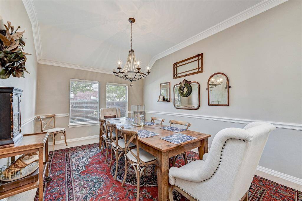This dining room features  soft gray walls, crown molding, and a decorative chandelier. Two windows provide natural light.