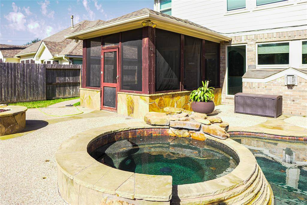 This backyard features a cozy screened porch, a small pool with stone accents, and a neatly landscaped patio area, perfect for relaxation and entertaining.