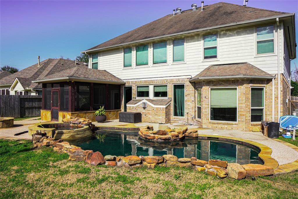 This photo showcases a charming two-story home with a backyard featuring a small pool surrounded by natural stone accents. A screened patio offers a cozy outdoor living space, perfect for relaxation and entertainment.