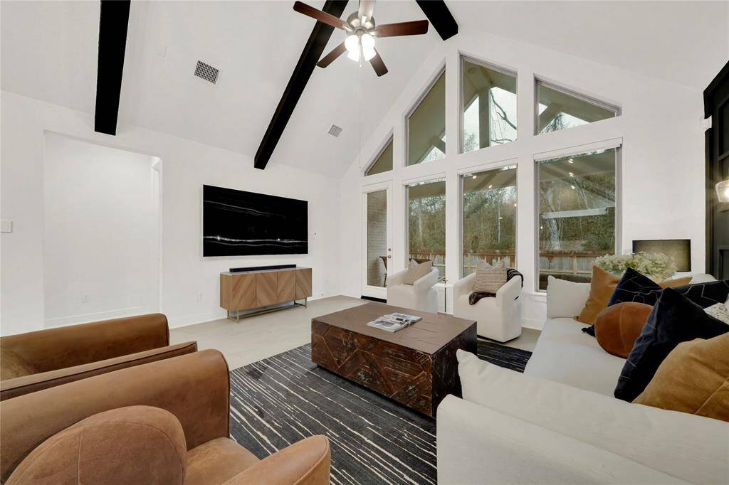 Large windows provide ample natural light and showcase views of the outdoors.  This sleek entertainment setup offers a comfortable and inviting atmosphere.