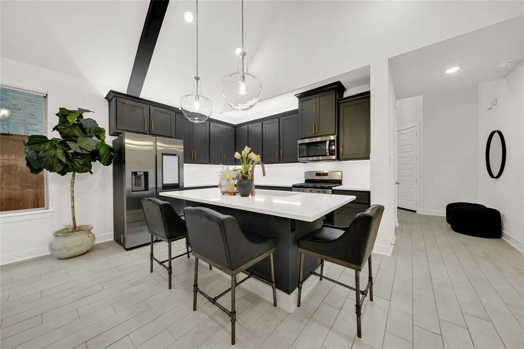 The open layout includes a cozy breakfast bar that can seat 3-4 and is next to the dining area. The stylish wood-look tile flooring creates a sophisticated and functional space.
