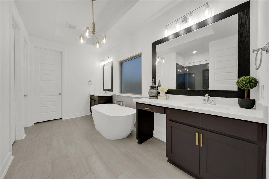 Primary bath with stand alone soaking tub and double vanities with updated framed mirrors