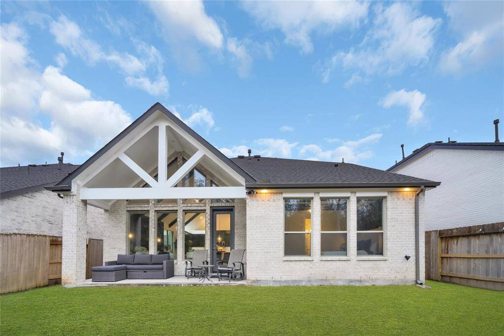 This home features a modern exterior with a spacious backyard and a covered patio area, perfect for outdoor relaxation and entertaining.