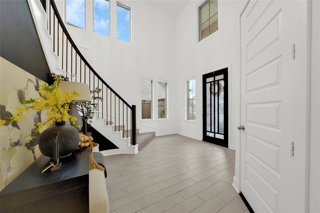 Step into a bright and spacious entryway with high ceilings, large windows, and the signature Westin spiral staircase. The front door features elegant glass paneling, and the neutral tile flooring complements the contemporary decor.