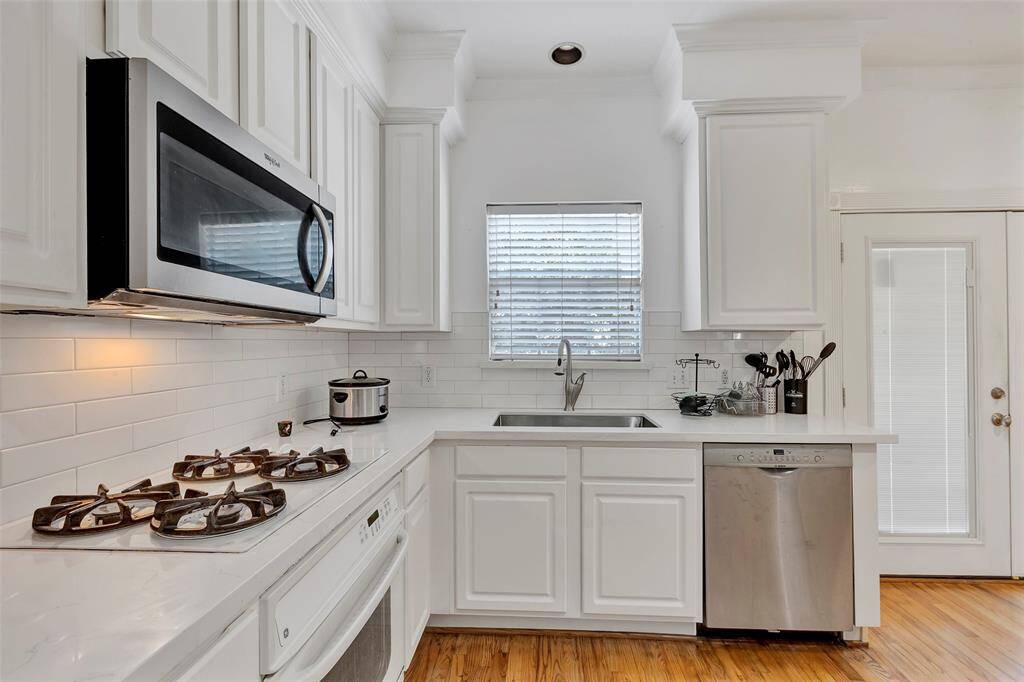 A secondary bathroom featuring a walk-in shower with glass doors and a pedestal sink, complemented by white tiling throughout.