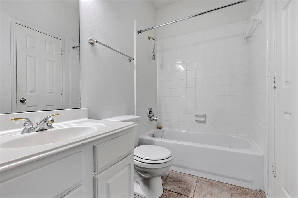 This is a spacious, well-lit bathroom featuring a large vanity with dual sinks, ample storage, a full-sized mirror, and modern fixtures. The neutral color palette offers a clean and serene atmosphere.