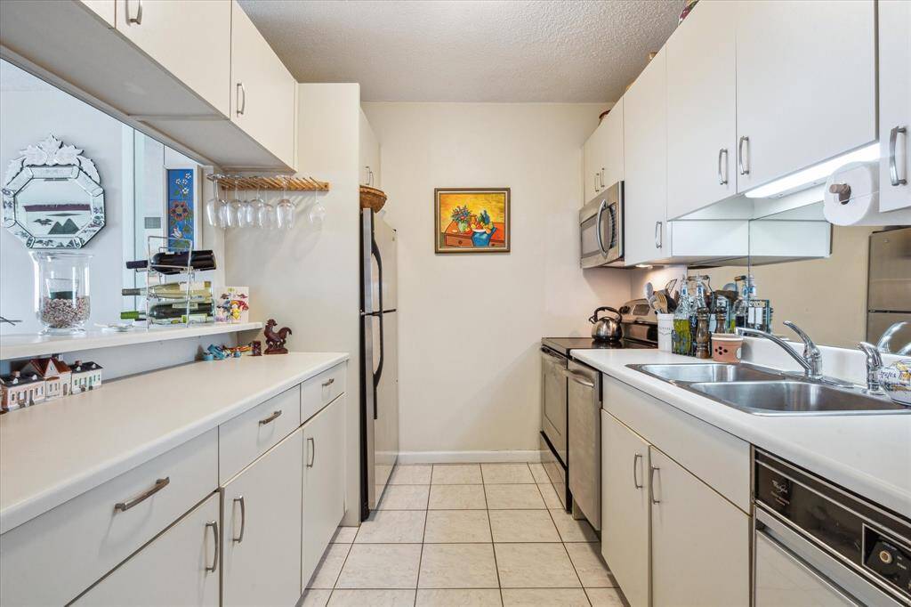 Stylishly coastal white kitchen featuring stainless steel appliances and a peninsula perfect for meal preparation and entertaining.