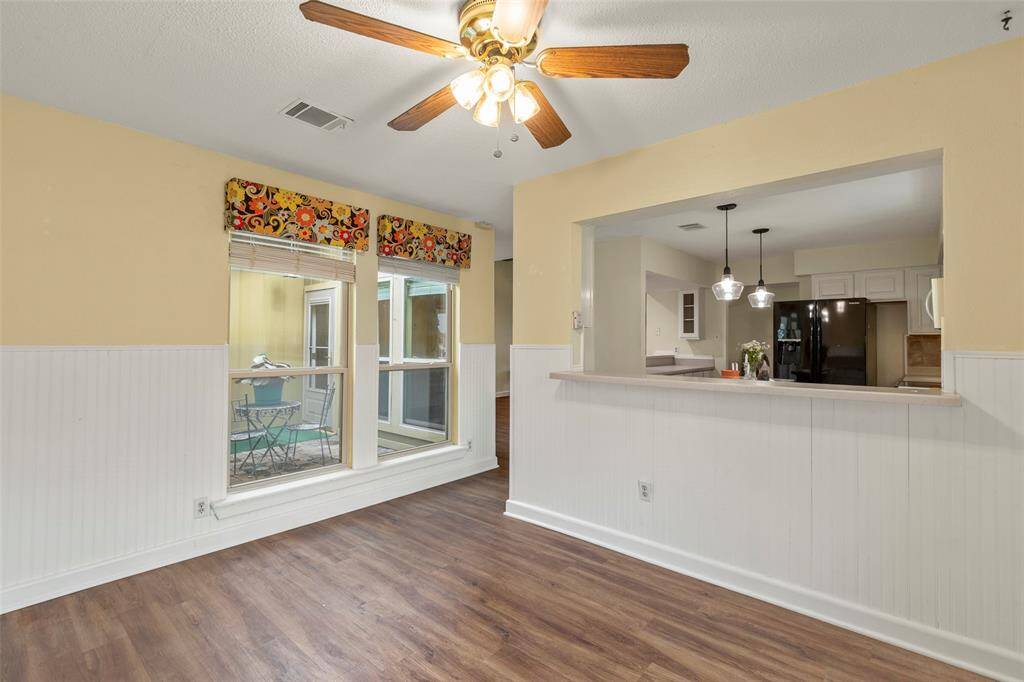 Breakfast Room with beadboard, breakfast bar opening to kitchen, ceiling fan with light, views to the courtyard.