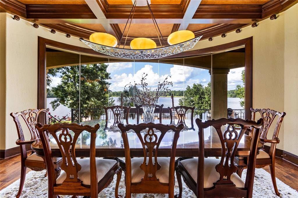 This dining room boasts elegant wood, complemented by a stunning lake view through large butted glass windows, offering a serene backdrop for meals.