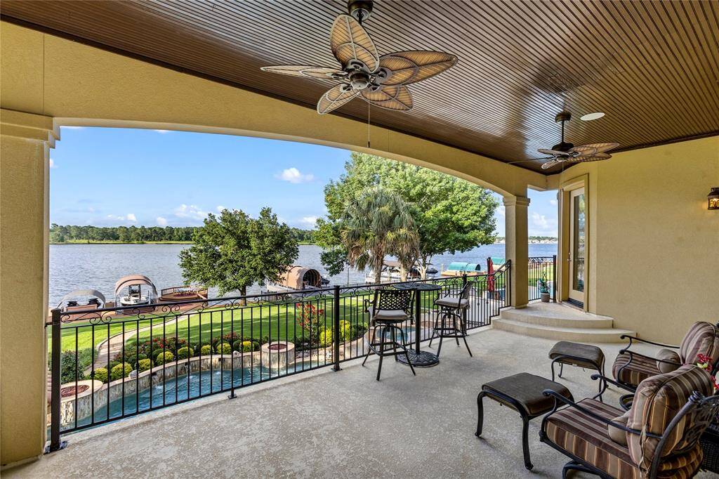 This is a spacious covered patio with ceiling fans, offering a serene lake view and direct access to a manicured lawn and private dock.