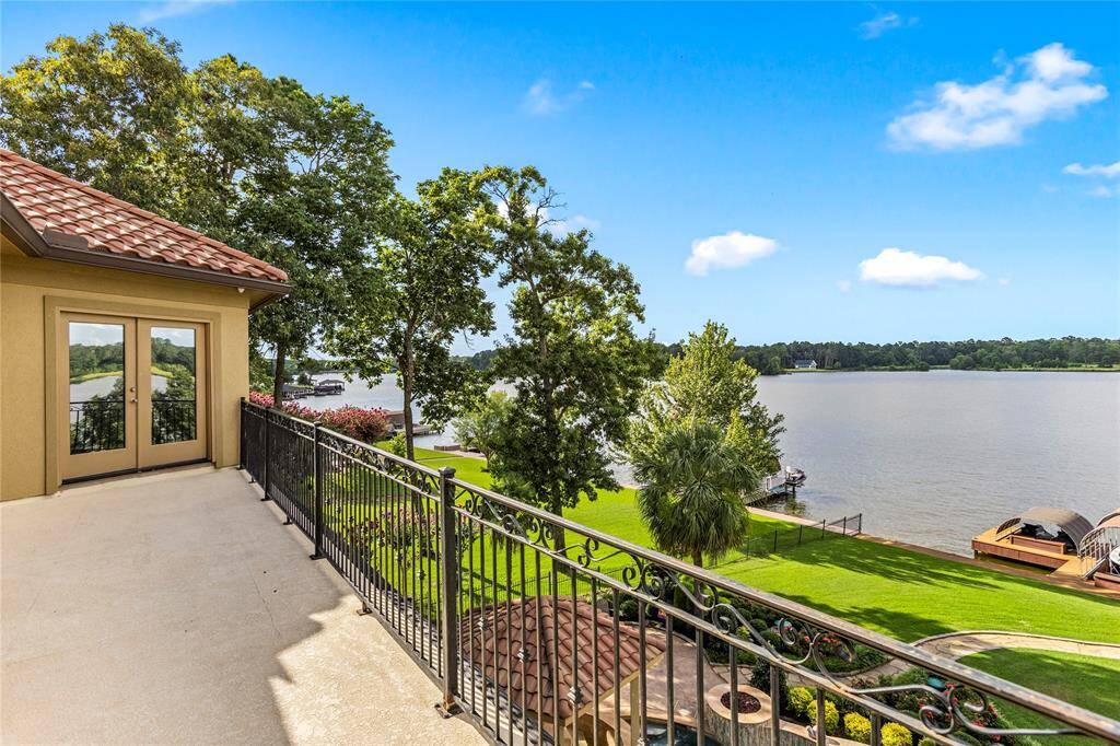 This is a spacious balcony with a scenic lake view, featuring ornate railings and surrounded by lush greenery, ideal for outdoor relaxation and entertaining.