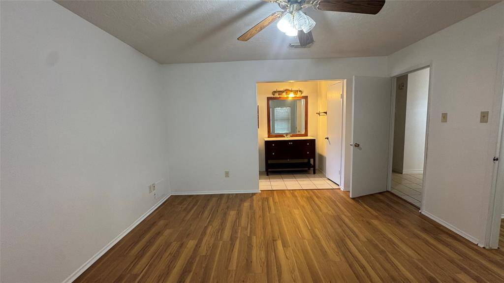 This is a single-story brick home featuring a two-car garage and a spacious driveway. The front yard is grassy with mature trees, offering a welcoming entrance.
