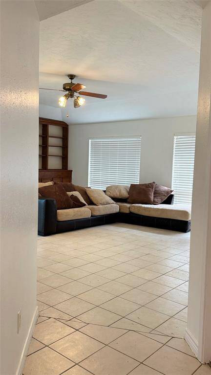 This is a single-story brick home featuring a two-car garage and a spacious driveway. The front yard is grassy with mature trees, offering a welcoming entrance.
