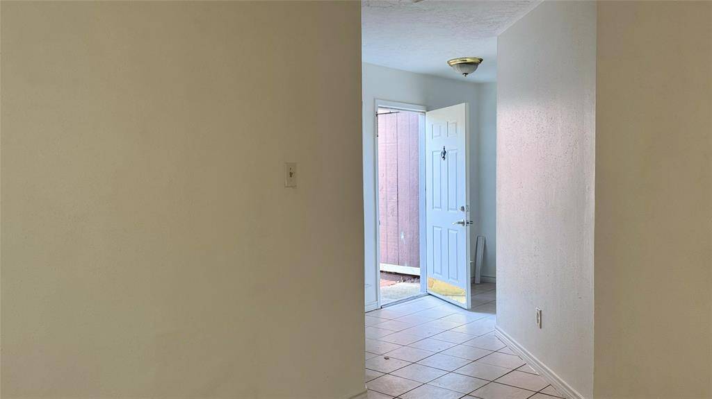 This is a single-story brick home featuring a two-car garage and a spacious driveway. The front yard is grassy with mature trees, offering a welcoming entrance.