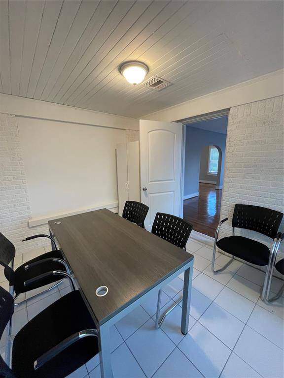 EXTRA FEATURE!! Modern office space with white brick walls and a tiled floor. It may also be used as another bedroom.