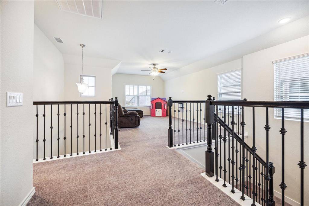 The landing at the top of the stairs is a transitional space that leads to various rooms, including a game room.