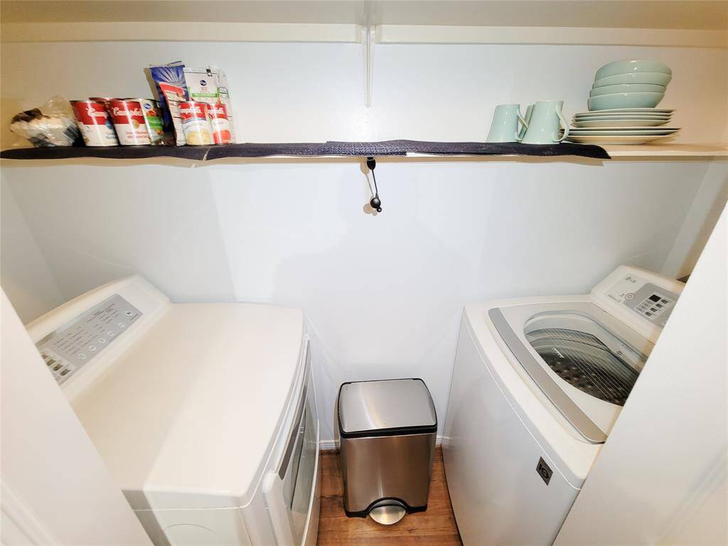 Compact laundry closet featuring a side-by-side washer and dryer with overhead shelving for storage, well-organized and clean.