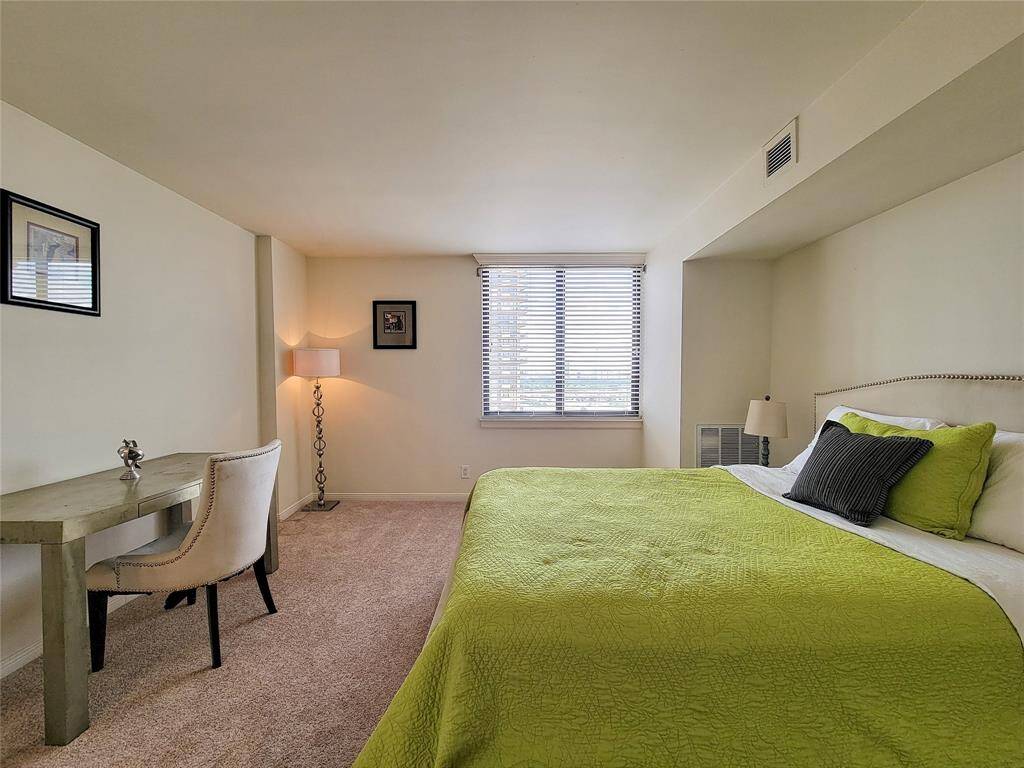 Spacious neutral-toned bedroom featuring fresh, new carpeting, includes a window with blinds, offering natural light.